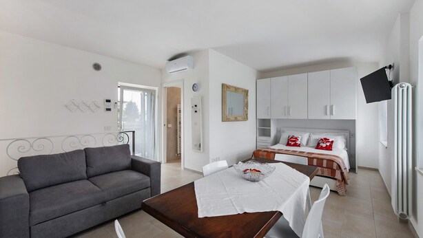 Una sala moderna con sofá, mesa de comedor y cama con cabecera.