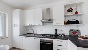 Una cocina moderna con armarios blancos, encimera negra, horno de acero inoxidable y cocina a gas.