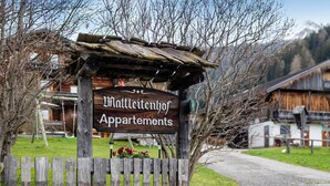 Un letrero de madera indica 'Mattleitenhof Apartments', con una valla de madera rústica al frente.
