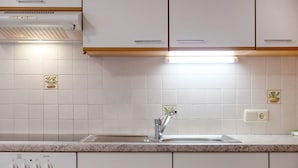 Una cocina con gabinetes blancos, un lavamanos de acero inoxidable y un horno empotrado.