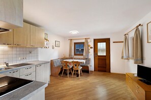 Eine kompakte Küche mit Einbauherd, Holzschränken und einem Essbereich mit einer Bank und Stühlen.