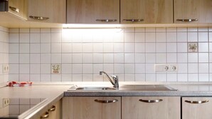 A kitchen with light wood cabinets, a stainless steel sink, and white tiled backsplash. - Apartment 'Rosenduft' with Mountain View, Shared Terrace and Wi-Fi (St. Magdalena gsies)
