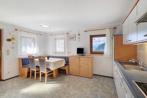 Une cuisine compacte avec des meubles en bois, une table à manger avec des chaises, un téléviseur et une fenêtre donnant sur un beau paysage.