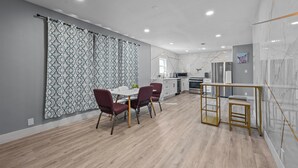 A modern kitchen with a dining area, featuring a marble backsplash, wooden flooring, and contemporary furniture. - Quirky & Stylish 3BR with Pool & Free Parking (Houston)
