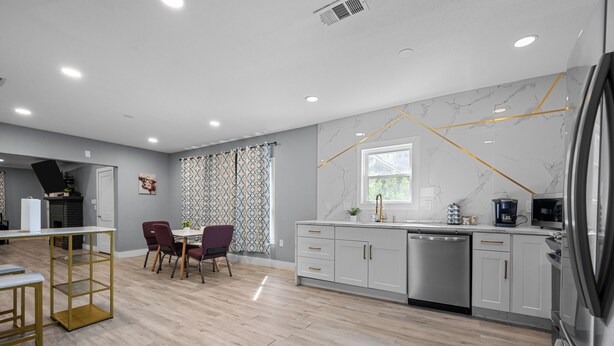 A modern kitchen with white cabinets, a stainless steel dishwasher, and a built-in oven. - Quirky & Stylish 3BR with Pool & Free Parking (Houston)