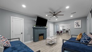 A modern living room with a fireplace, two sofas, a coffee table, and a television. - Quirky & Stylish 3BR with Pool & Free Parking (Houston)