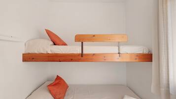 A bunk bed with a wooden headboard, a single bed below, and a pillow on the lower bed.