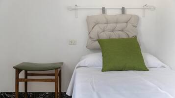 A bed with a headboard, a green pillow, and a wooden chair.