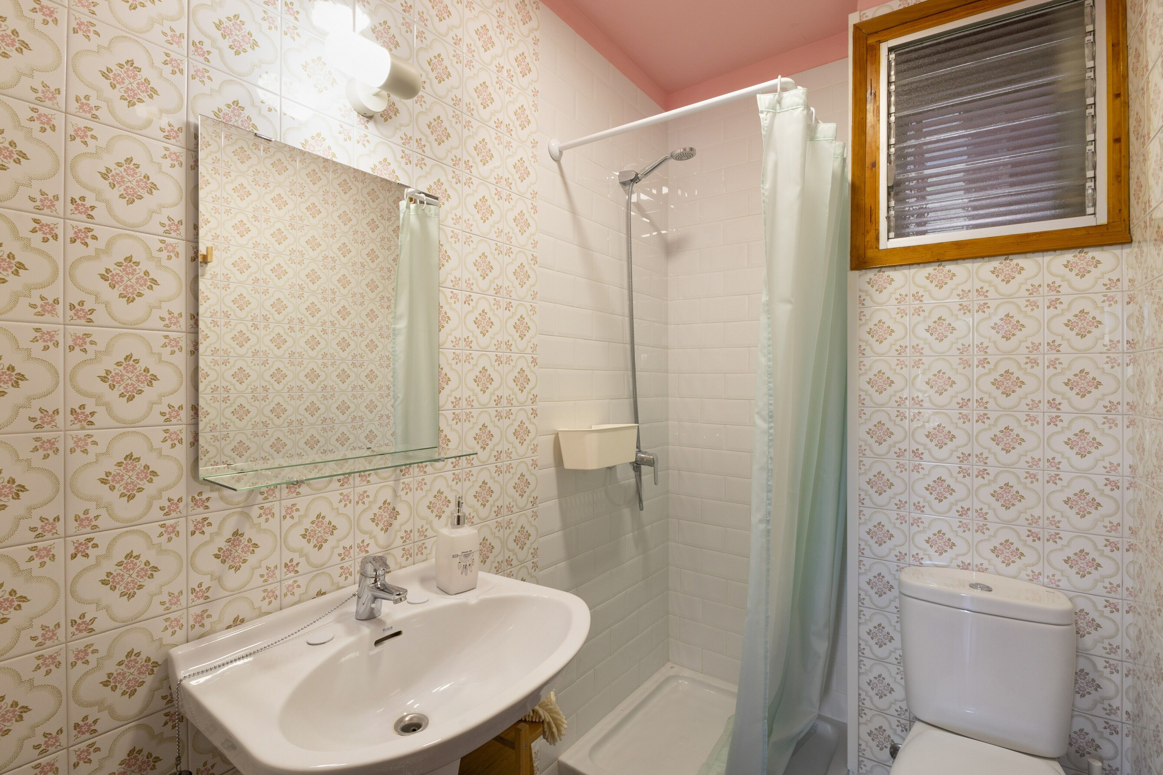 Un baño con ducha, lavabo, inodoro y espejo.