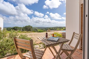 Mesa y sillas de madera en un patio con vistas a un paisaje y una piscina.