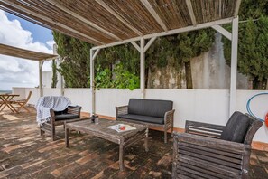 Une terrasse extérieure avec des meubles en bois, une table et un espace salon abrité.