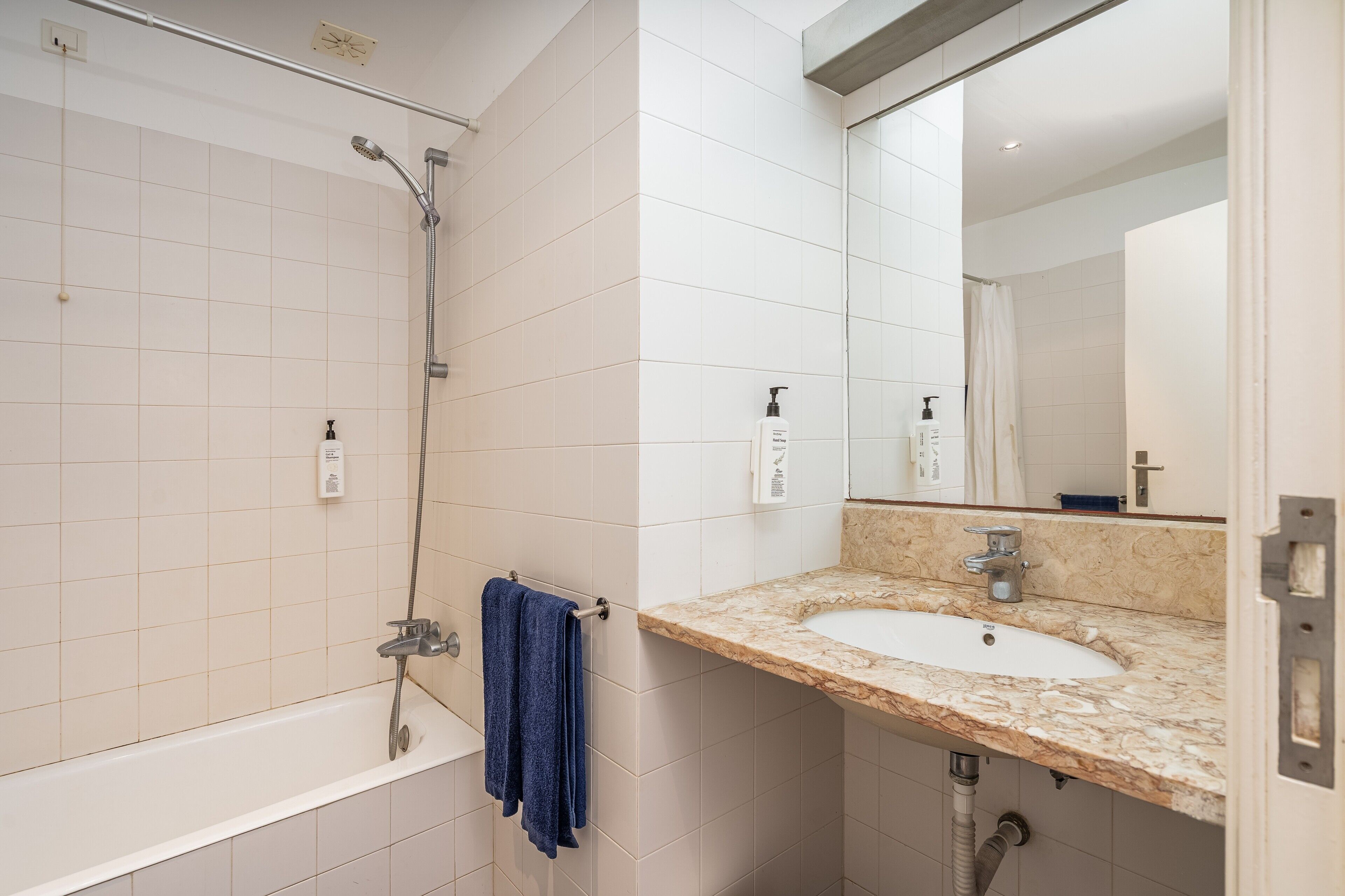 A bathroom with a bathtub, a shower, a sink, and a mirror.