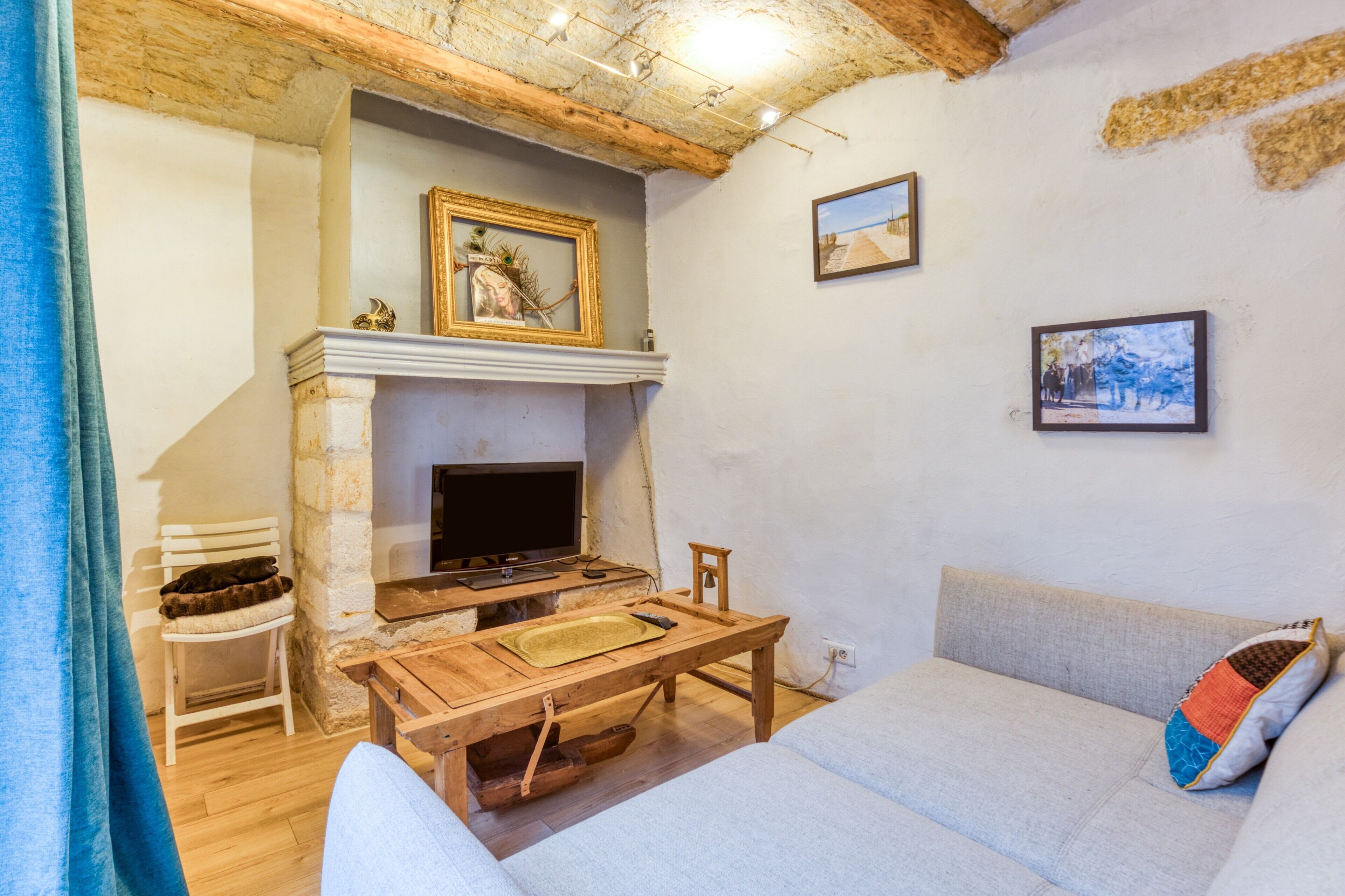 A cozy living room with a fireplace, a television, a wooden table, a sofa, and a chair.