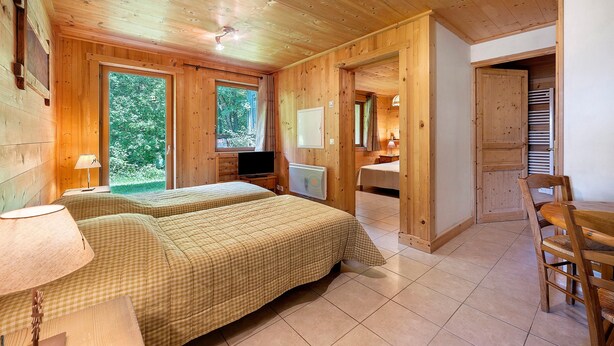 A wooden cabin with two beds, a TV, and a dining area.