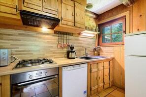 Una cocina con armarios de madera, cocina a gas, lavavajillas y una ventana con vistas.