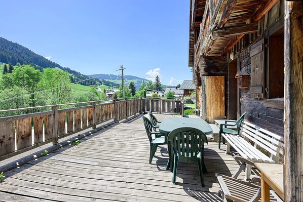 A wooden deck with outdoor furniture, overlooking a mountainous landscape.