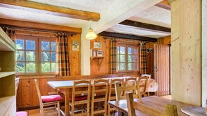 Un intérieur en bois avec une table à manger, des chaises et une fenêtre avec des rideaux.