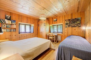 Una cabaña de madera con dos camas, un escritorio y una estantería.