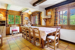 Comedor con una larga mesa de madera, sillas y vistas a zonas verdes.