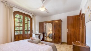 A bedroom with a bed, a wardrobe, a mirror, and a ceiling fan.
