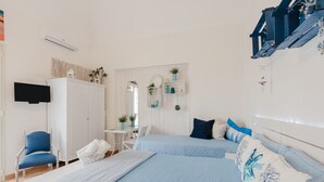 Une chambre avec deux lits, une chaise, une table et un téléviseur.