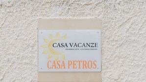 Une enseigne avec les inscriptions « CASA VACANZE » et « CASA PETROS » sur un mur à texture.