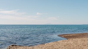 A beach with a rocky shoreline and calm water.