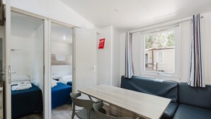 Une pièce avec une table en bois, deux lits, un canapé et une fenêtre avec des rideaux.