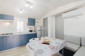 A compact kitchen with a dining area, a microwave, a refrigerator, and a table with a patterned tablecloth.
