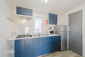 A kitchen with blue cabinets, a gas stove, a microwave, and a refrigerator.