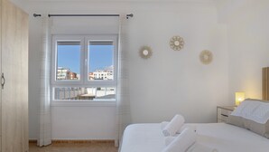 Una habitación de hotel con cama, una ventana con cortinas, una mesita de noche y decoración en la pared.