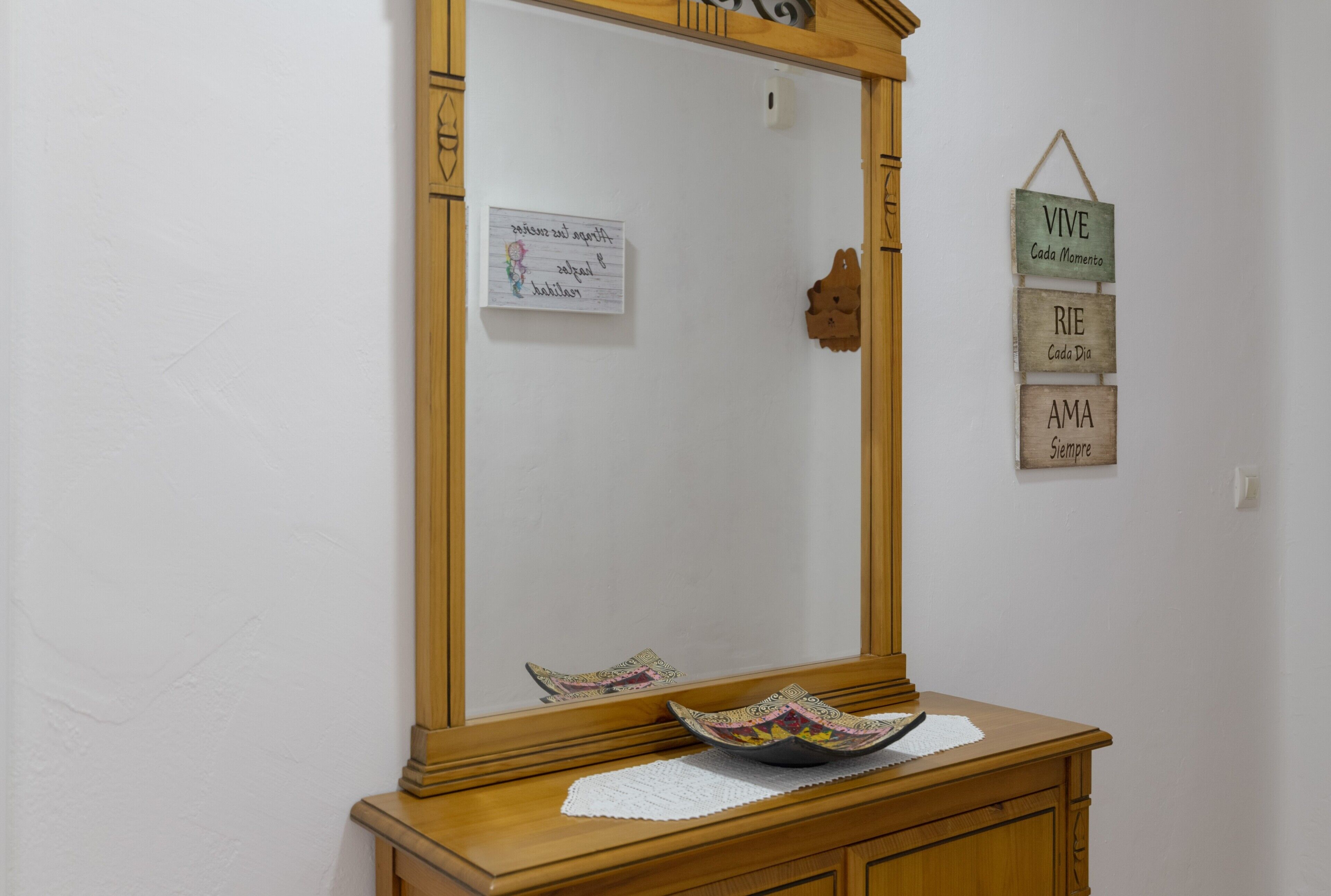 A wooden dresser with a mirror, a decorative bowl, and a small sign with handwritten text.