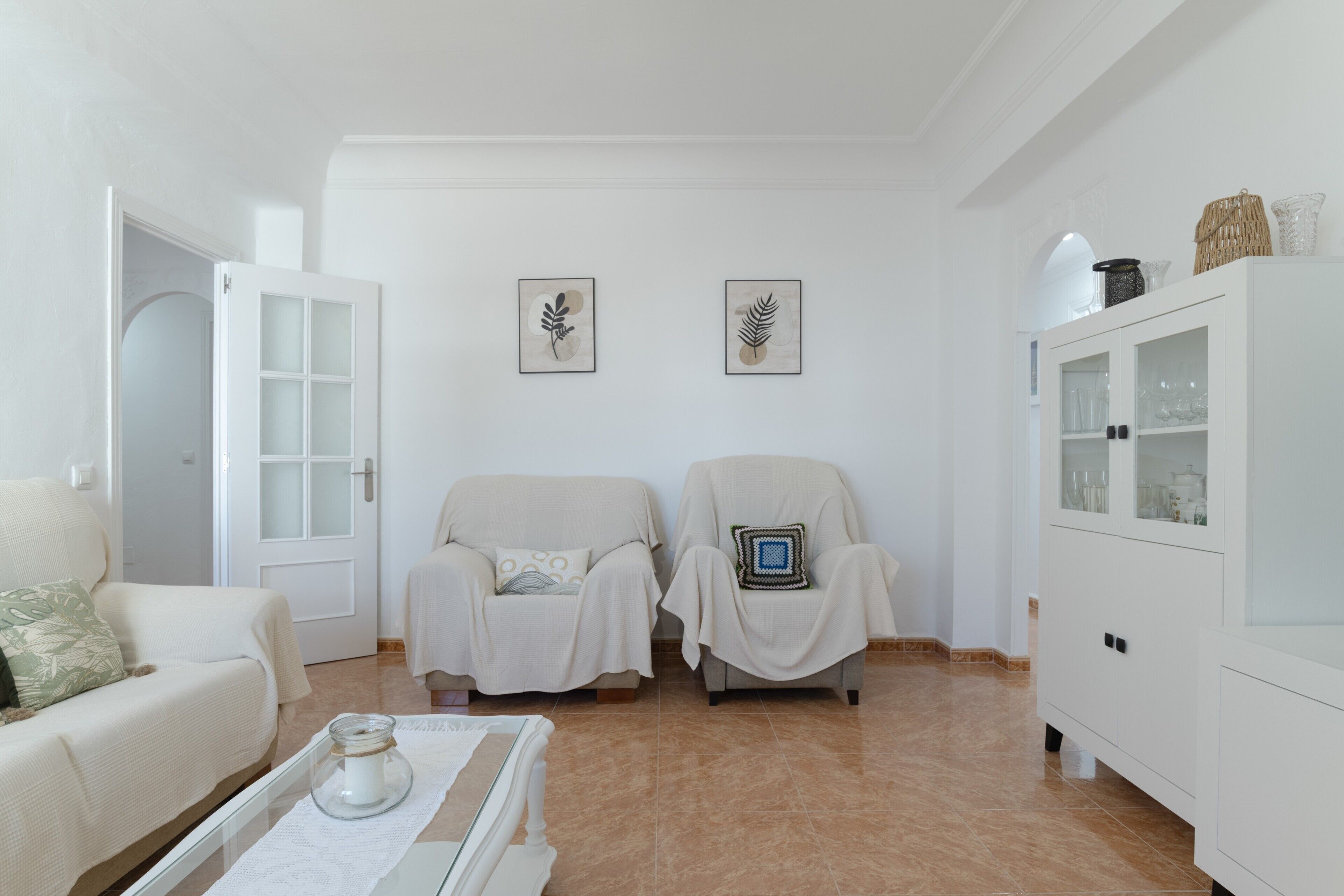 Un salon comprenant deux fauteuils, un canapé, un meuble et deux œuvres d’art accrochées au mur.