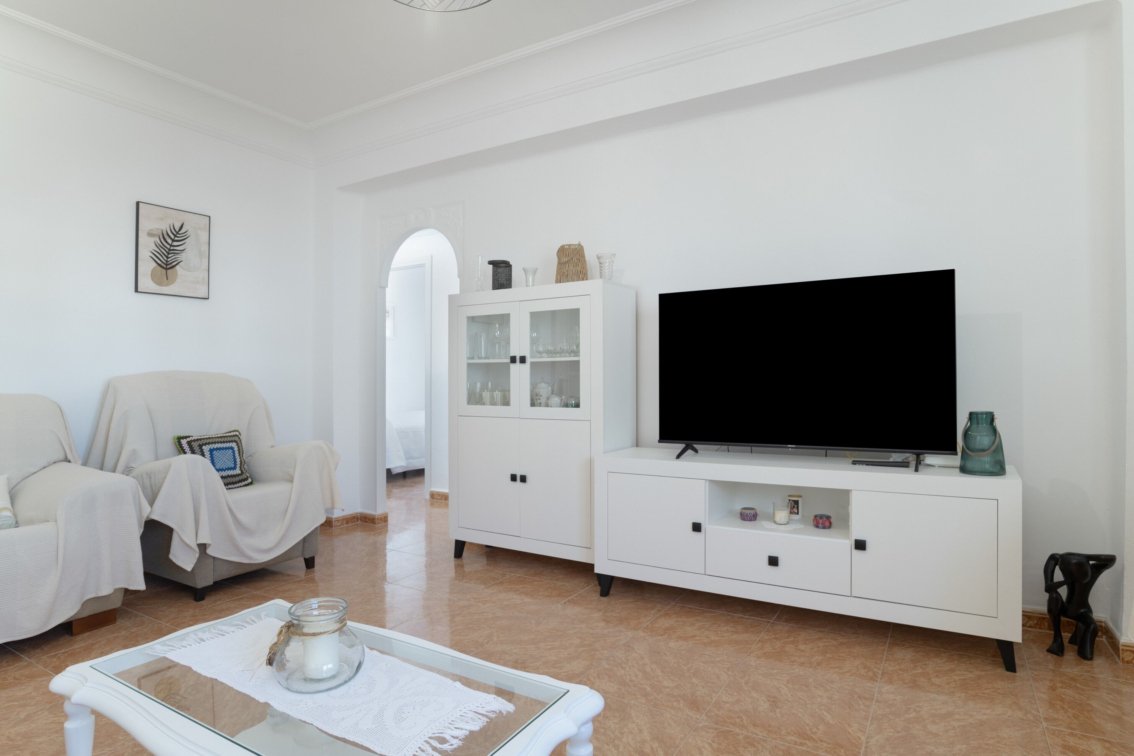 A living room with a sofa, a television, a cabinet, and a coffee table.