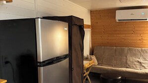 A compact kitchen with a stainless steel refrigerator, a wooden cabinet, a beige sofa, and a patterned rug. - Charming 1-bedroom mini cottage in enjoyable Punta Gorda with WiFi, AC (Punta Gorda)