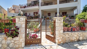Un edificio de varios pisos con un portón de piedra, plantas en macetas y balcones.