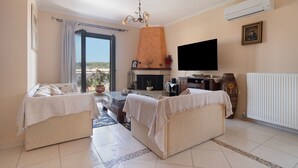Una sala de estar con dos sofás, una televisión, una chimenea y un ventanal grande.