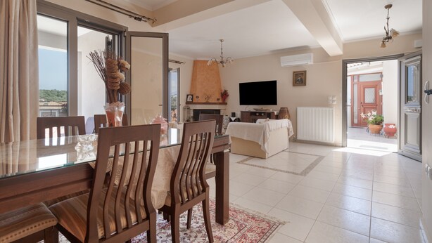 Un amplio salón con una mesa de comedor, sillas, sofá, televisor y chimenea.