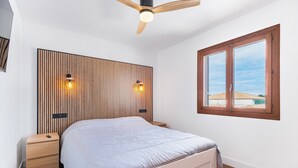 Ein Schlafzimmer mit Bett, Holz-Kopfteil, Nachttischen, Deckenventilator und einem Fenster mit Aussicht.