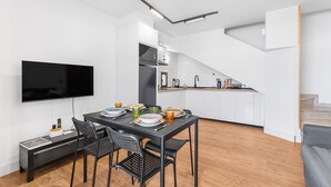 Eine moderne Küche mit weißen Schränken, einem schwarzen Kühlschrank und einem hölzernen Deckenventilator.