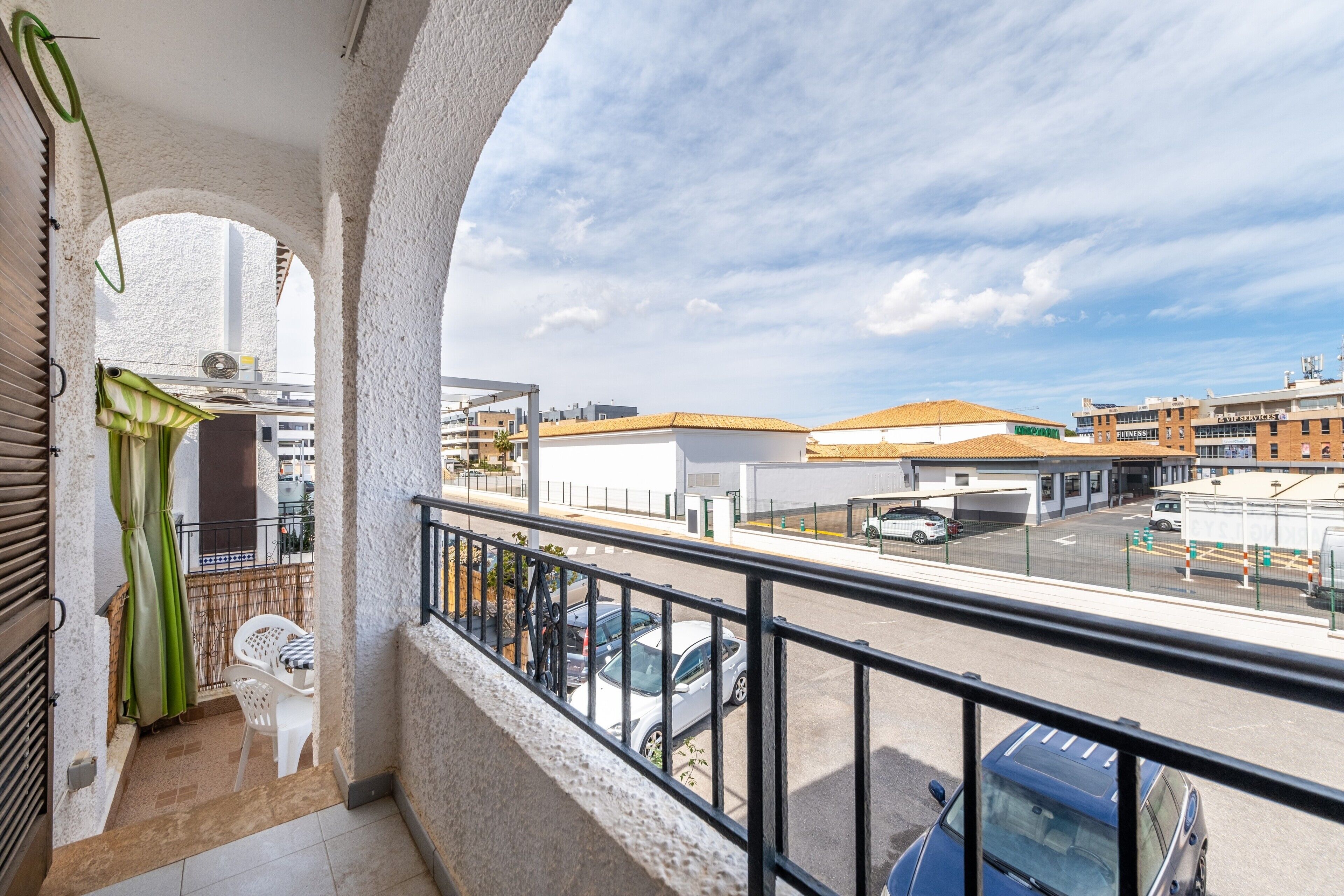 A balcony with a view of a parking lot and buildings.