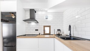 Eine moderne Küche mit weißen Schränken, einem Edelstahlkühlschrank, einer schwarzen Dunstabzugshaube und einer Holz Arbeitsplatte.