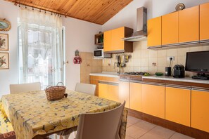 A kitchen with orange cabinets, a dining table with a yellow tablecloth, and a basket on the table.