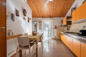 A kitchen with wooden cabinets, a dining table with chairs, and a window with curtains.