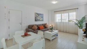 Un salon avec un canapé, une table basse, une table à manger et un tableau accroché au mur.