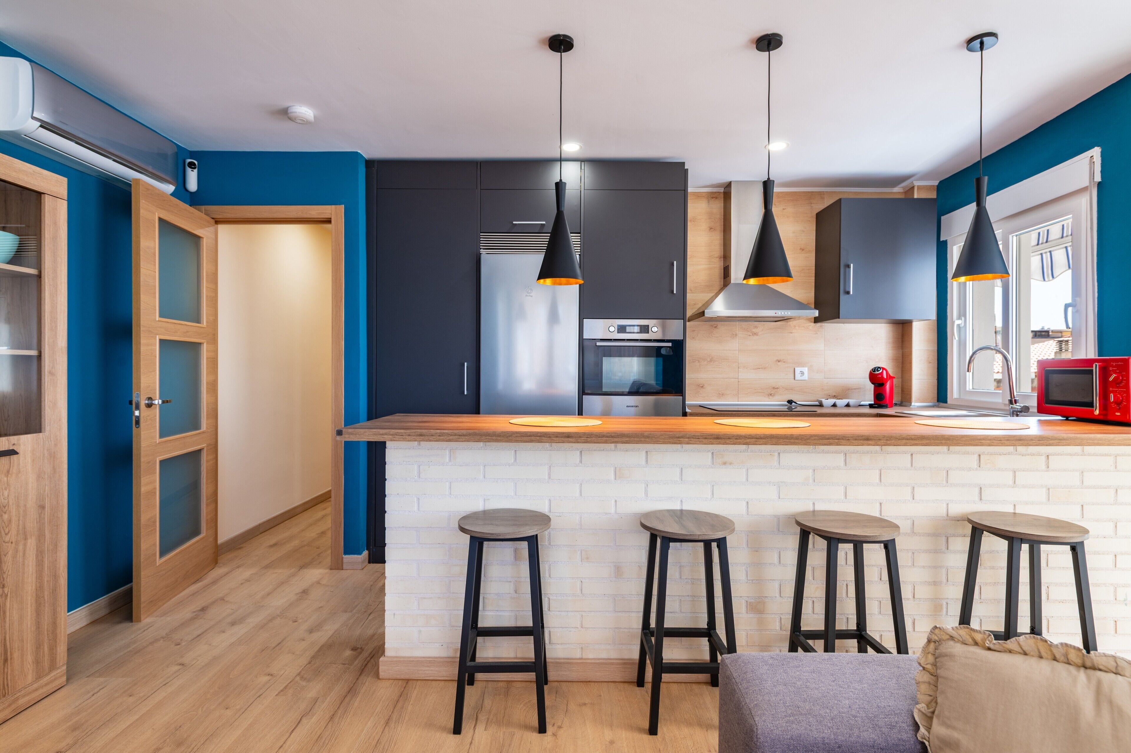 A modern kitchen with a central island, bar stools, and pendant lighting.