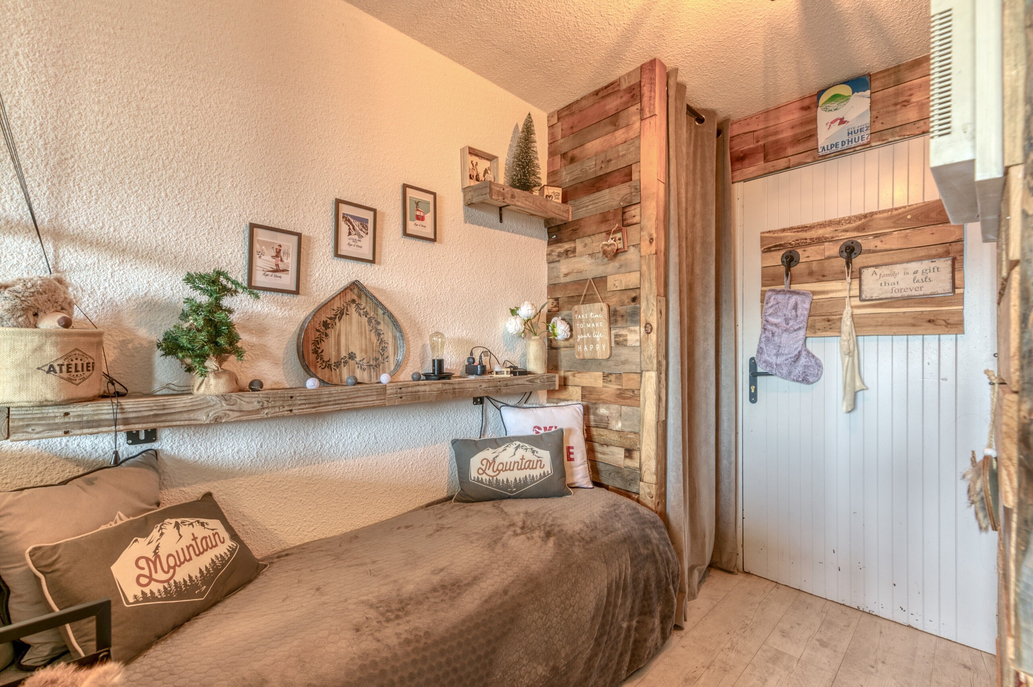 A cozy room with a bed, a wooden shelf with various items, a small plant, and a door with a sign.