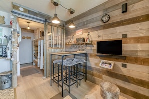 Zona de bar con taburetes, un televisor y un letrero que dice 'café'.