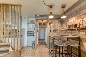 Una cocina compacta con detalles de madera, una barra con taburetes y un refrigerador a la vista.
