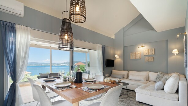 A dining area with a table set for four, a sofa, and a TV in a room with a view.
